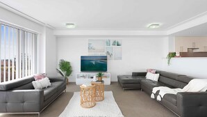 Un salon moderne avec deux canapés, un téléviseur et une grande fenêtre.