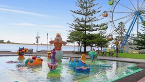 Un parc aquatique doté d’une grande roue, de toboggans colorés et d’une statue imposante au centre.