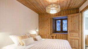 Ein Schlafzimmer mit Holzboden, einem Bett mit weißer Bettwäsche und einem Fenster mit Blick nach draußen.
