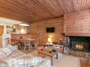 Ein gemütliches Blockhaus-Interieur mit Essbereich, Sofasofa und Kamin.