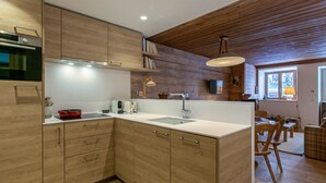 Eine moderne Küche mit Holzschnitzereien, einem eingebauten Backofen, einer Spüle und einem Essbereich mit Holztischen und -stühlen.