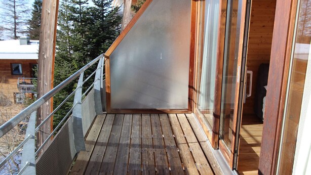A wooden deck with a metal railing, a sliding glass door, and a view of a forested area. - 6-person apartment in Chamrousse, south-facing, 2 bedrooms (Chamrousse)