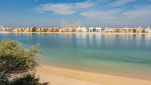 A coastal view with a clear sky, a calm sea, and a row of buildings along the shore. - Sparking signature Beach front villa reverera mediterian style in Palm Jumeirah  (Dubai)
