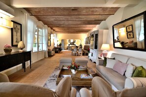 Ein geräumiges Wohnzimmer mit hoher Decke, Kamin und einer gemütlichen Sitzecke mit Sofa und Sesseln.