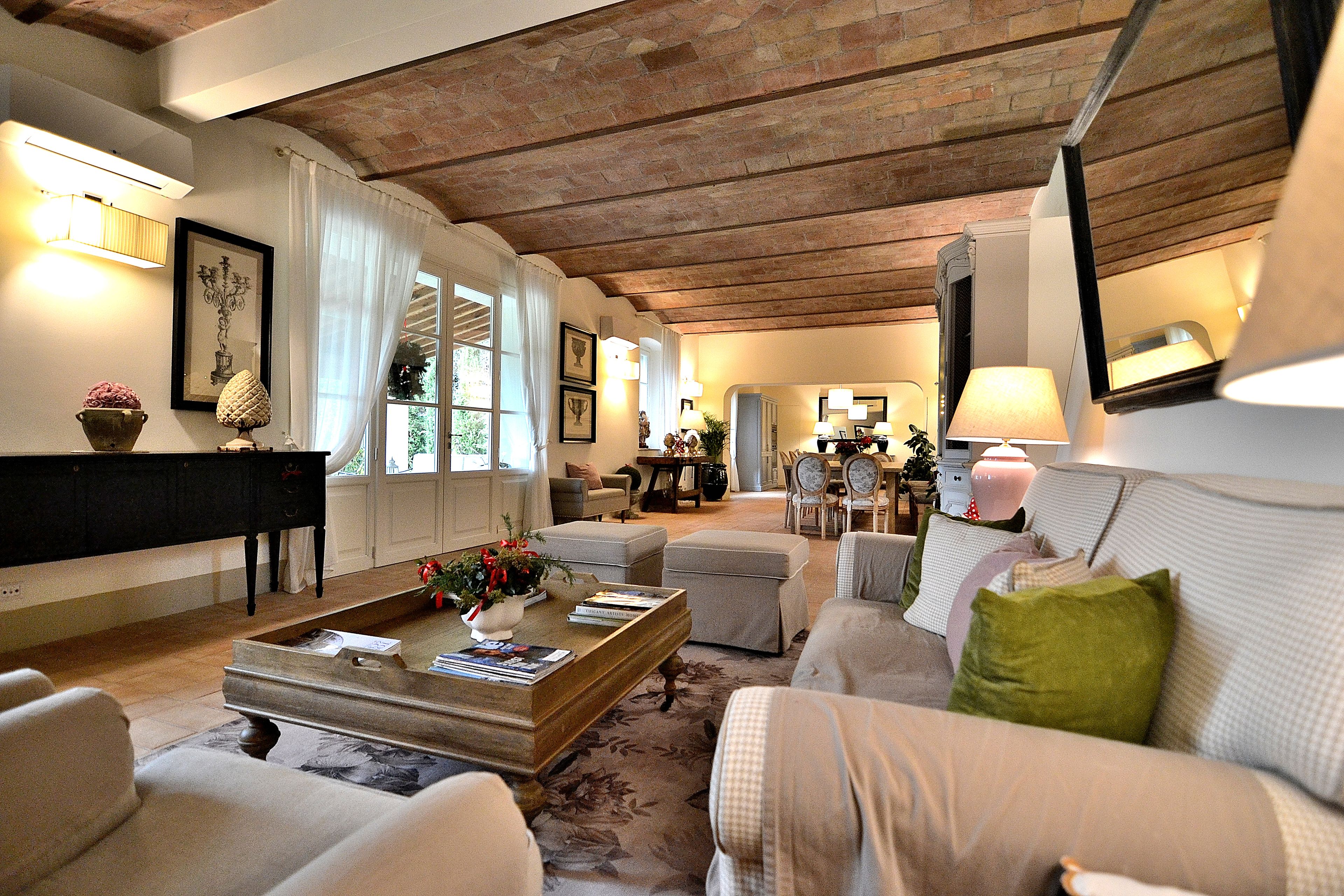 Ein geräumiges Wohnzimmer mit hoher Decke, einem Klavier und einem Essbereich im Hintergrund.