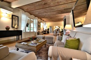 Un vaste salon doté d’un haut plafond, d’un piano et d’un coin repas situé à l’arrière-plan.