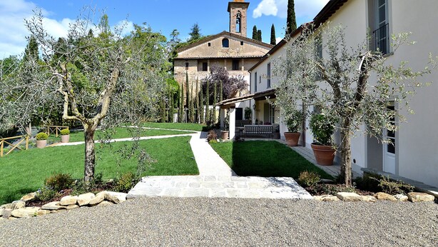A building with a stone pathway leading to a door, surrounded by trees and a well-maintained lawn. - Exlusive luxury villa with private pool in the heart of Tuscany (Linari)
