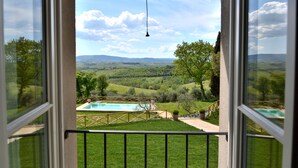 A view from a window overlooking a swimming pool, grassy yard, and rolling hills. - Exlusive luxury villa with private pool in the heart of Tuscany (Linari)