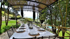 An outdoor dining area with a covered table set for a meal, surrounded by chairs and a pergola structure. - Exlusive luxury villa with private pool in the heart of Tuscany (Linari)