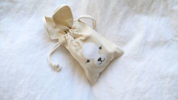 Una pequeña bolsa de cordón con un diseño de conejito sobre un fondo de tela blanca.