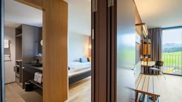 Una habitación de hotel moderna con cama, mesita de noche, lámpara y vistas al exterior.