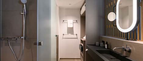 Un baño moderno con ducha, tocador con espejo y un perchero para toallas.
