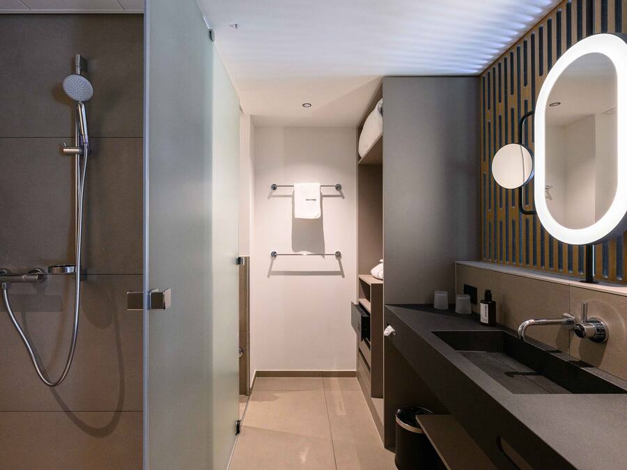 Un baño moderno con ducha, tocador con espejo y un perchero para toallas.