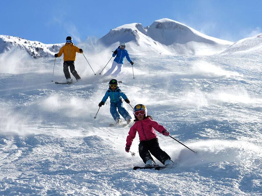 Pista de esquí nevada con esquiadores.