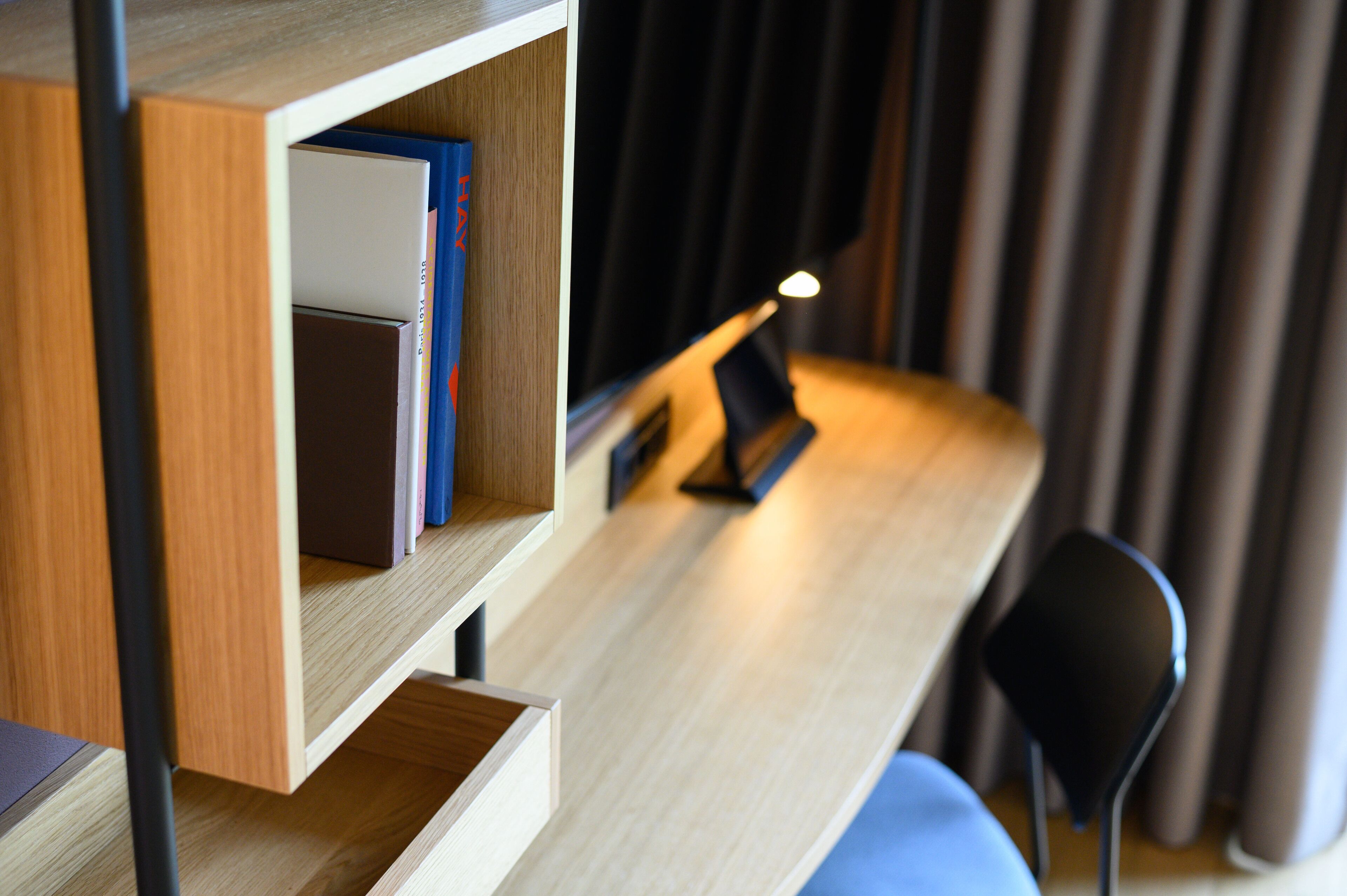 Une chambre moderne avec un bureau en bois, une chaise et une bibliothèque remplie de livres.