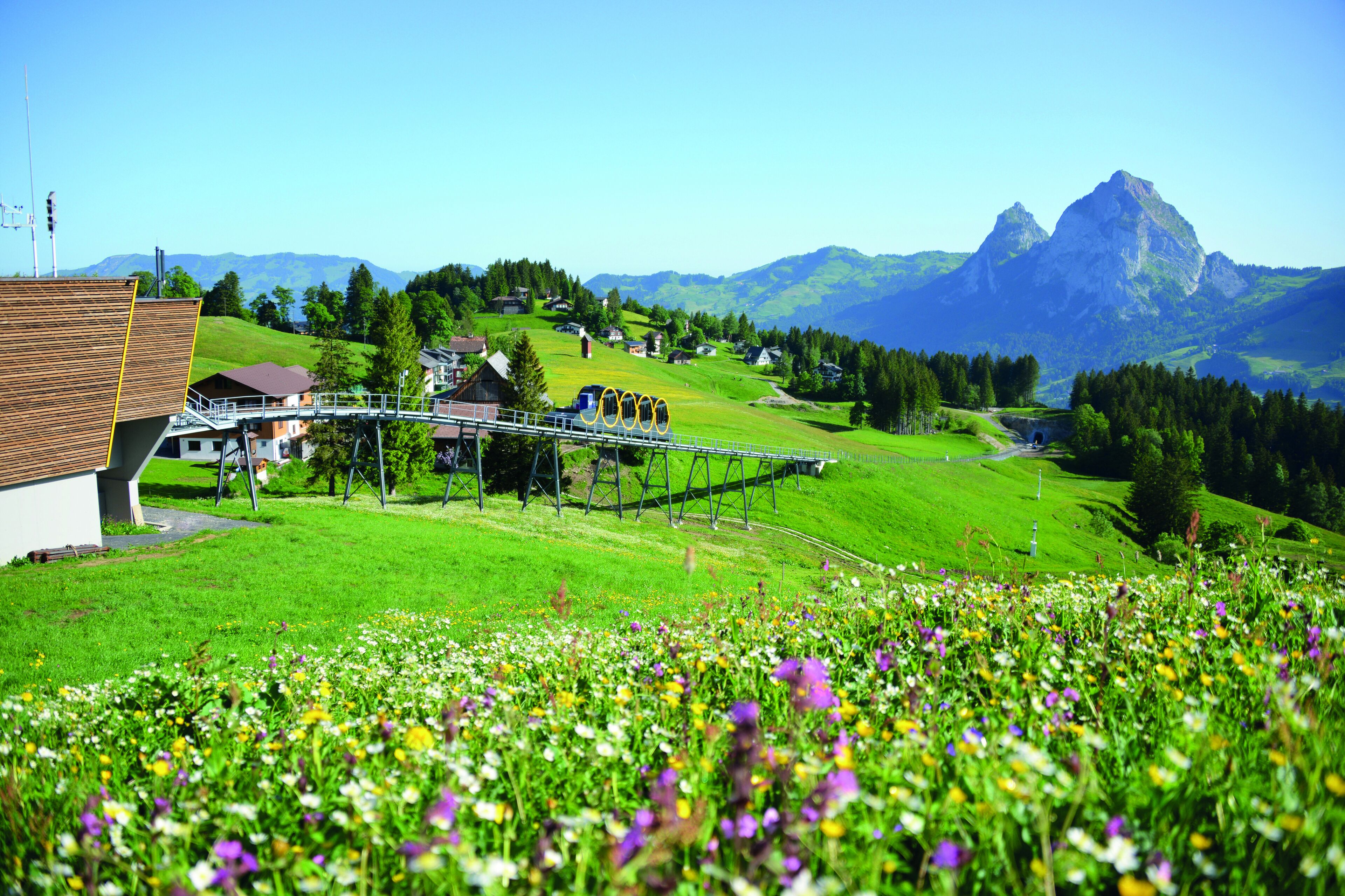 Ländliche Landschaft mit einem Holthaus, einer Brücke und einem Berg im Hintergrund.