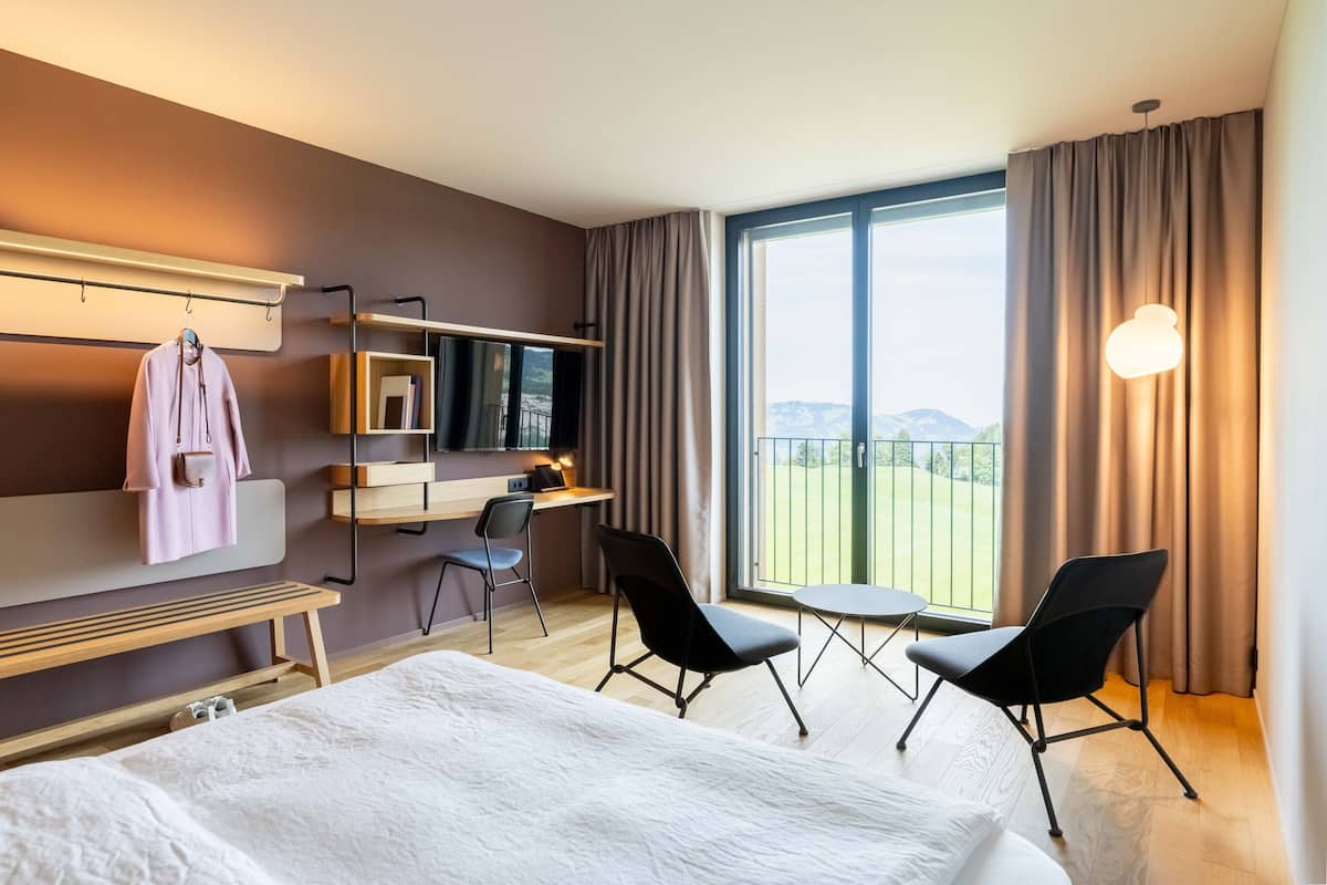 Hotellihuone, jossa on sänky, työpöytä, tuoli, televisio ja näkymä ulos.