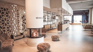 A modern interior with a fireplace, seating, and a visible store named 'stoos'. - Stoos Lodge (Morschach)