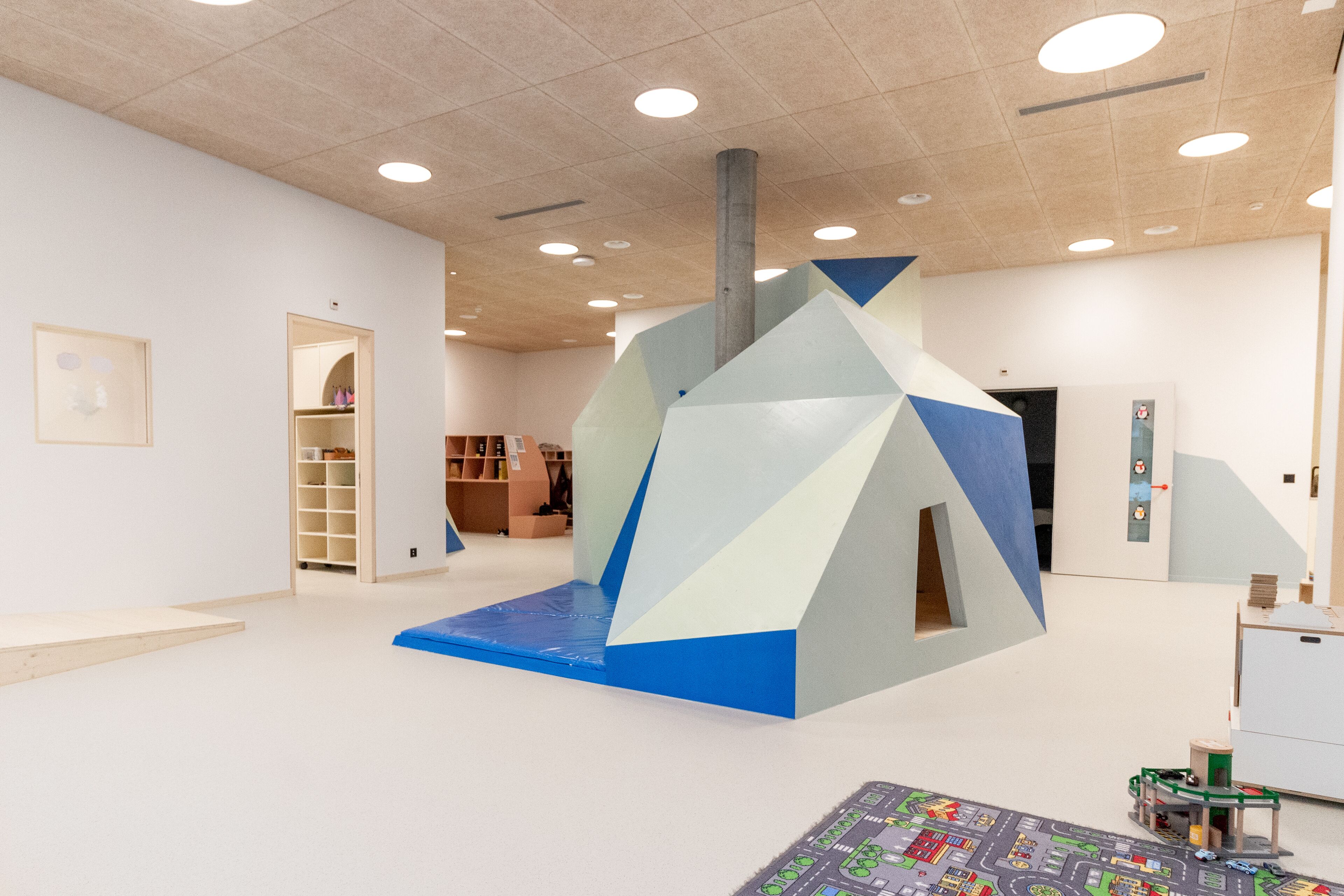 Un interior moderno con una estructura geométrica, un área de juegos para niños y un gran mapa en el suelo.