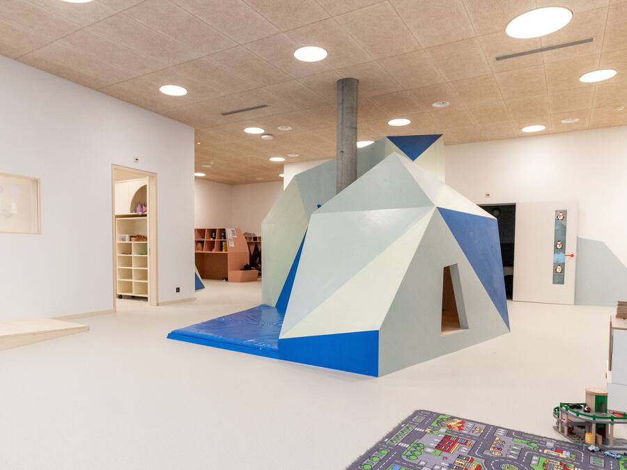 Un interior moderno con una estructura geométrica, un área de juegos para niños y un gran mapa en el suelo.