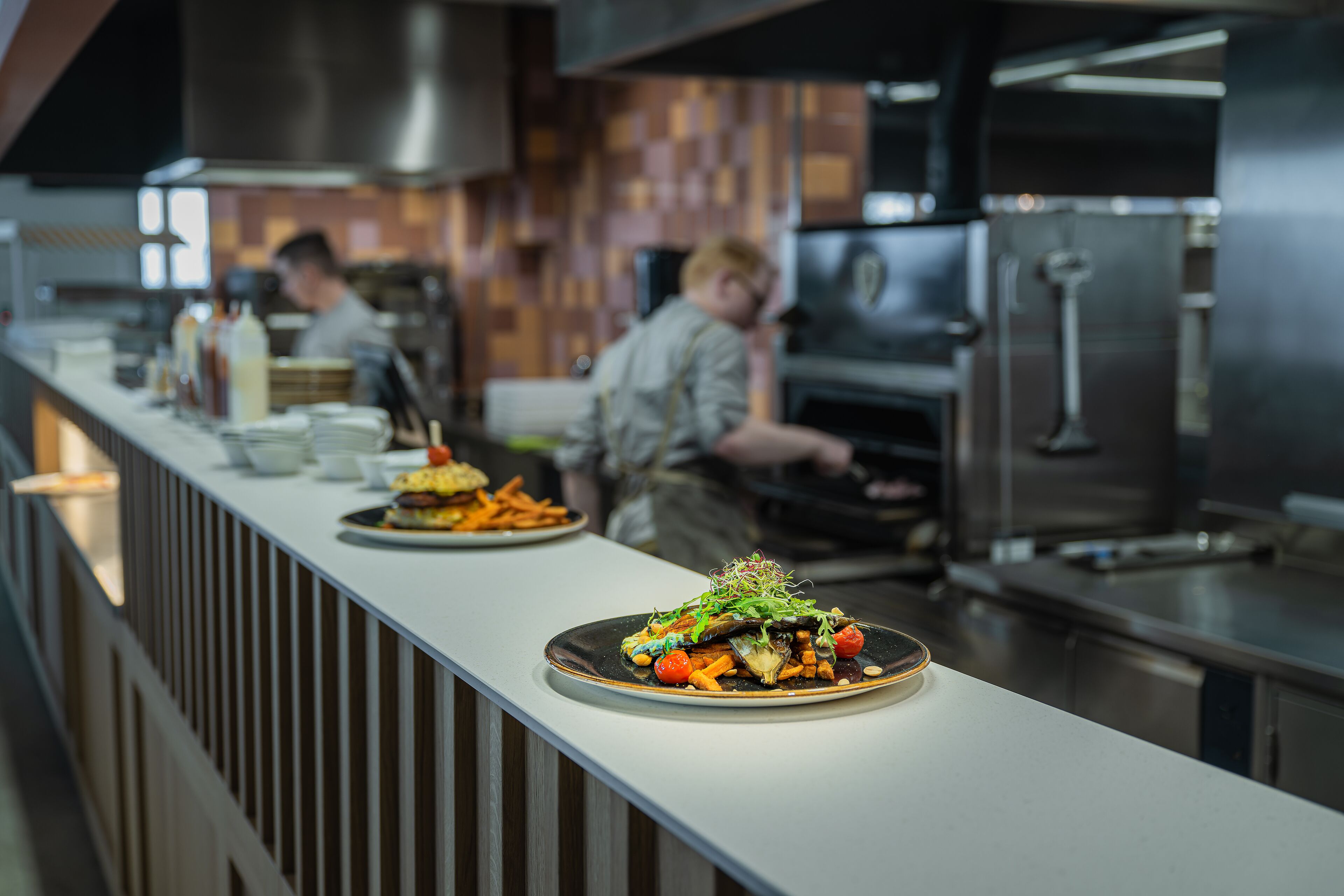 Una cocina moderna con electrodomésticos de acero inoxidable y una encimera amplia que exhibe un plato servido.