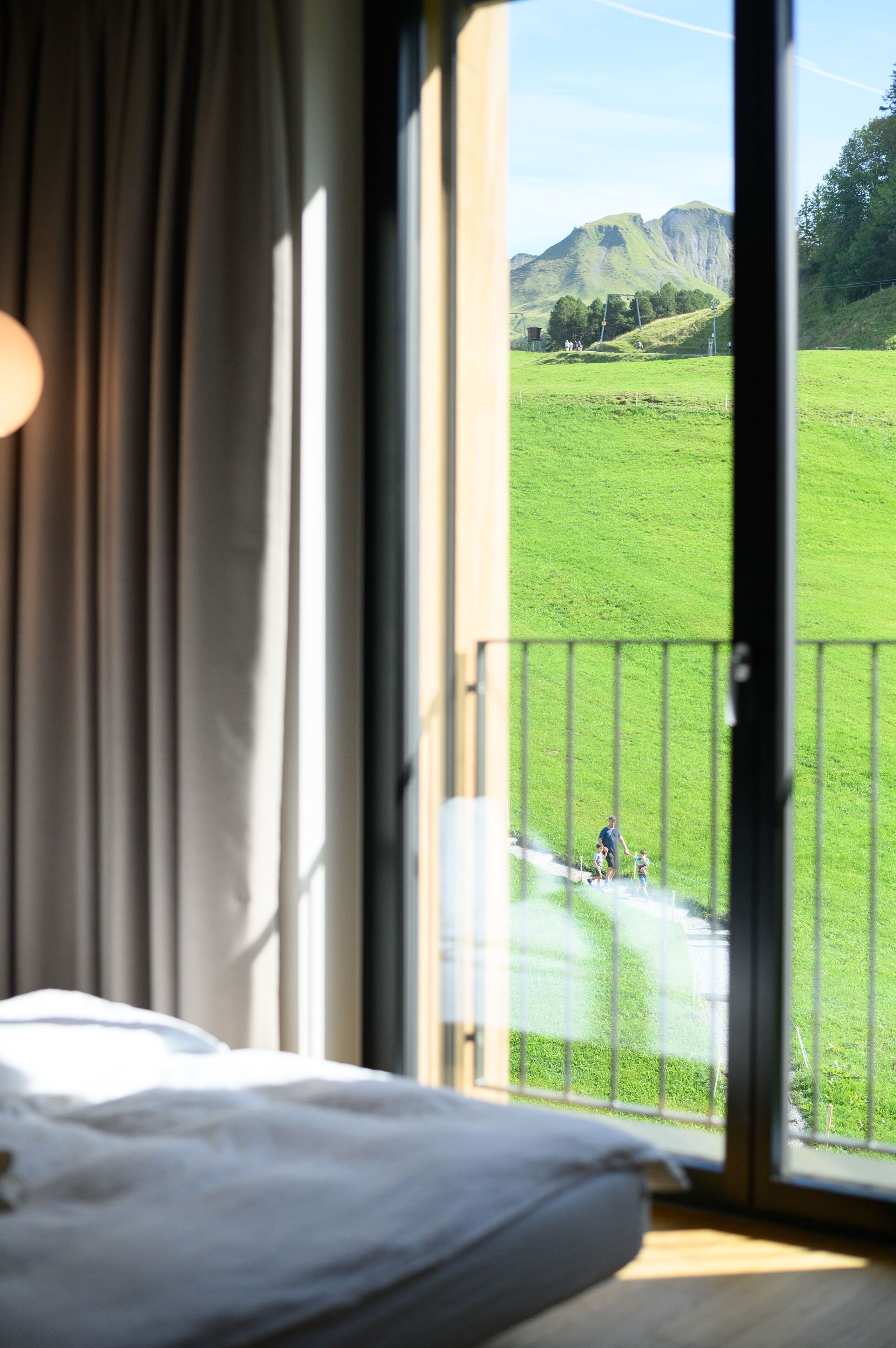 Una camera da letto con una grande finestra che si affaccia su un prato verde e montagne.