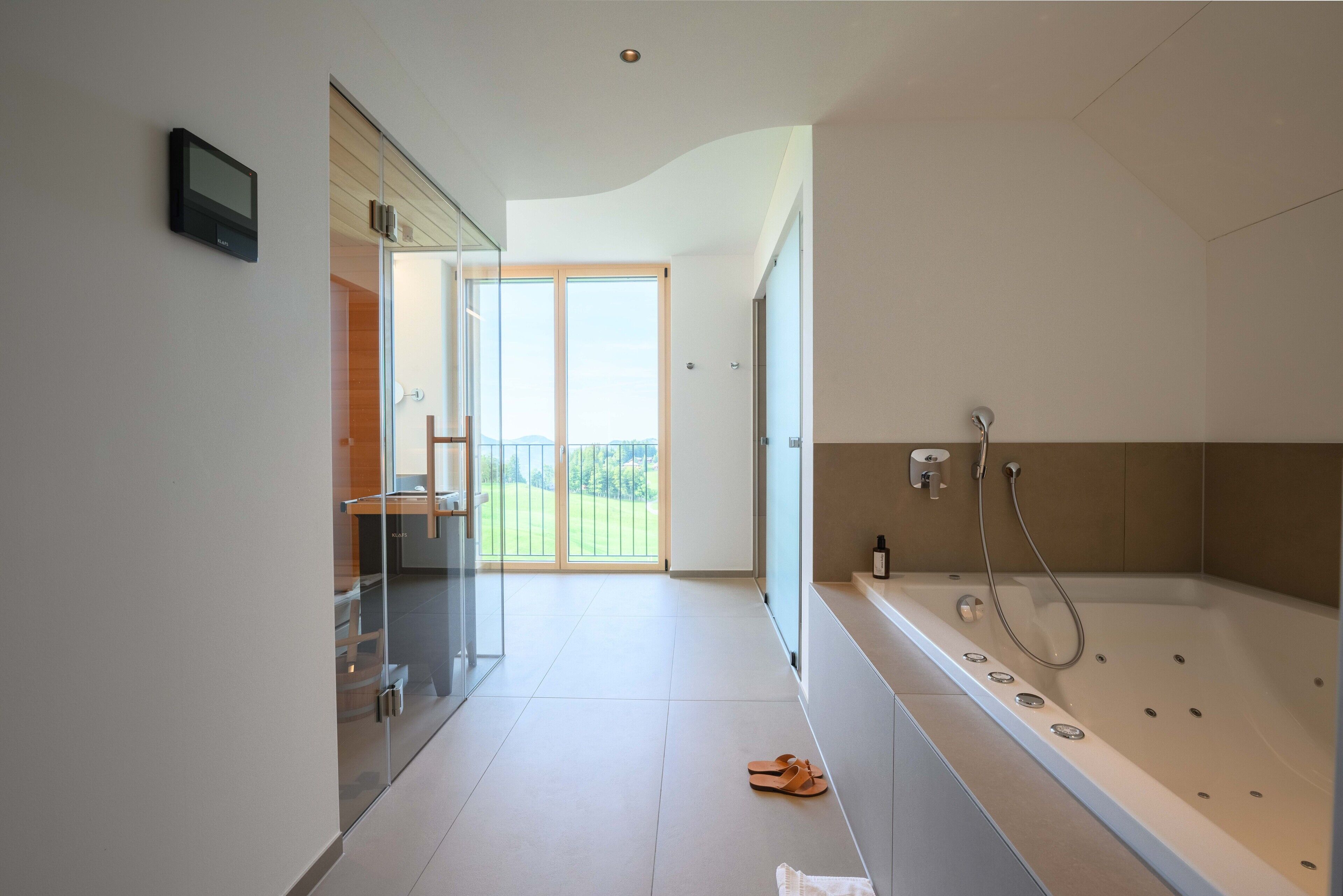Une salle de bain moderne dotée d’une grande baignoire, d’une douche à parois de verre et donnant sur un balcon.