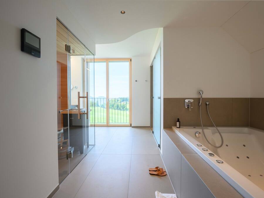 Une salle de bain moderne dotée d’une grande baignoire, d’une douche à parois de verre et donnant sur un balcon.