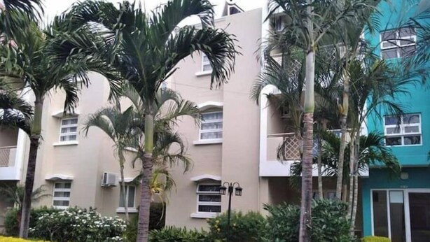 A multi-story building with balconies, surrounded by well-maintained greenery and palm trees. - La Marquise Apartment with pool (Flic en Flac)