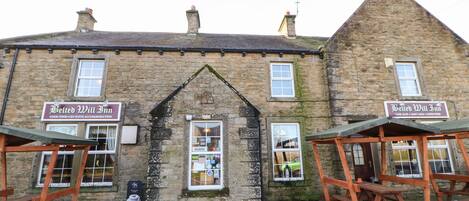 A traditional stone building with two signs reading "Belted Will Inn" and a window displaying various items.