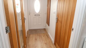 A hallway with wooden doors and a white door with a circular window. - Stable Cottage (Brampton)