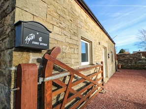 Un bâtiment en pierre avec une porte en bois et une boîte aux lettres portant l’inscription « Stable Cottage ».