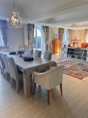 A dining area with a large table, chairs, and a chandelier.