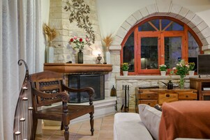Una sala de estar acogedora con chimenea, muebles de madera y plantas decorativas.