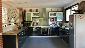Una cocina moderna con armarios oscuros, un refrigerador de acero inoxidable y piso de baldosas.