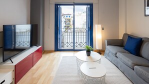 A modern living room with a grey sofa, a red cabinet, a TV, and a balcony with blue doors. - Lucas House by Sitges Group (Sitges)