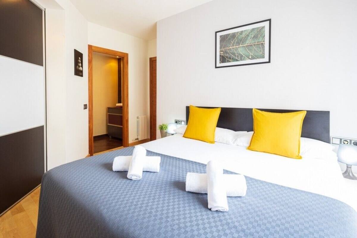 A hotel room with a bed, a framed picture on the wall, and a door leading to a hallway.