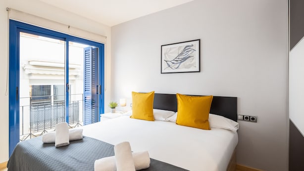 A hotel room with a bed, two yellow pillows, a white blanket, and a framed artwork on the wall. - Lucas House by Sitges Group (Sitges)