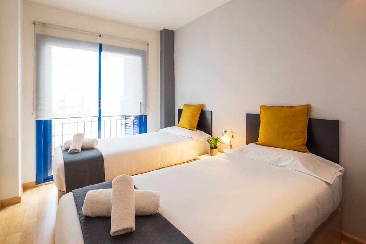 A hotel room with two beds, a balcony, and a view of the city.