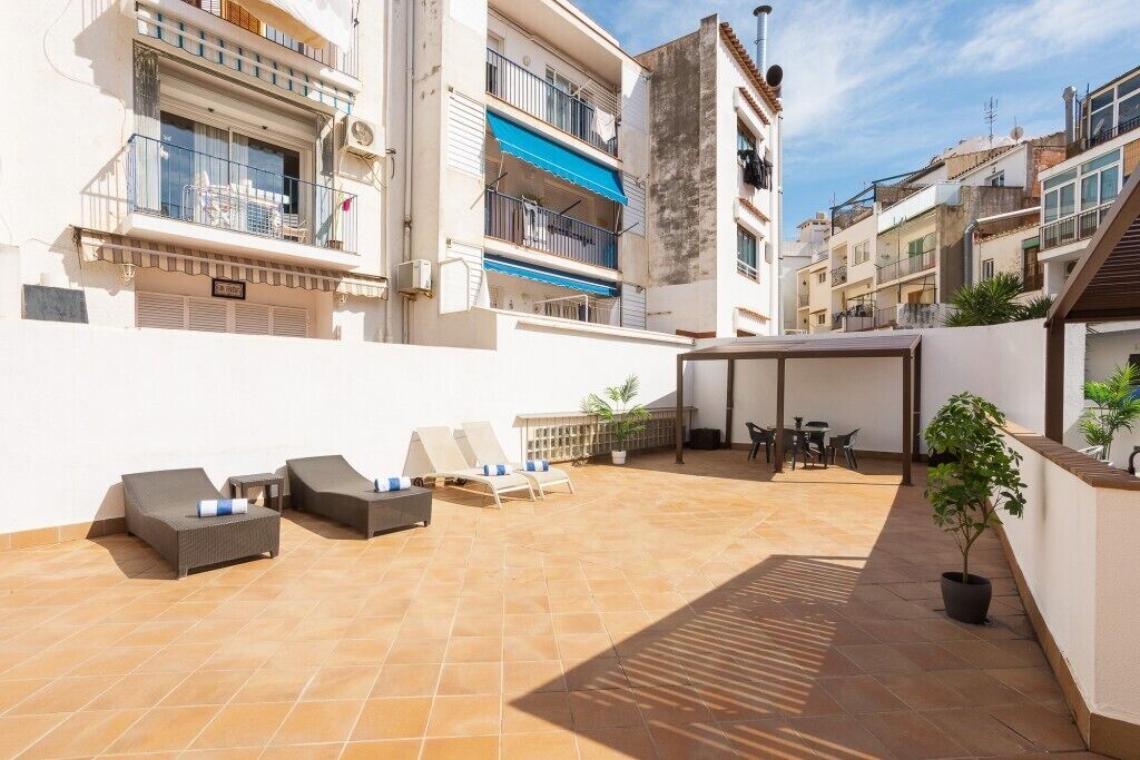 A rooftop terrace with outdoor seating, a covered area, and a potted plant.