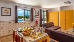 Un comedor con una mesa lista para el desayuno, un sofá y vistas al exterior.