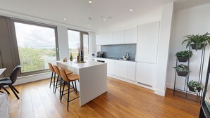 Une cuisine moderne avec des meubles blancs, un îlot central doté de tabourets, un four à micro-ondes et une cuisinière encastrée.