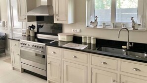 Una cucina moderna con mobili bianchi, un lavello in acciaio inossidabile e una finestra sopra al lavello.