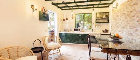 Una cocina con un armario verde, una mesa de comedor con sillas y una lámpara colgante.
