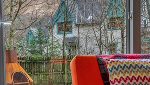 Une pièce chaleureuse avec une grande fenêtre, une table en bois et un coussin aux couleurs vives.