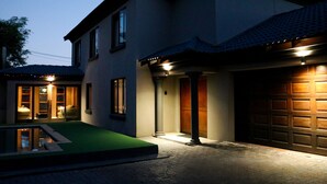 Una casa de dos pisos con garaje, piscina e ingreso bien iluminado.