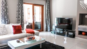 Una sala de estar moderna con sofá, mesa de centro, televisor y chimenea.