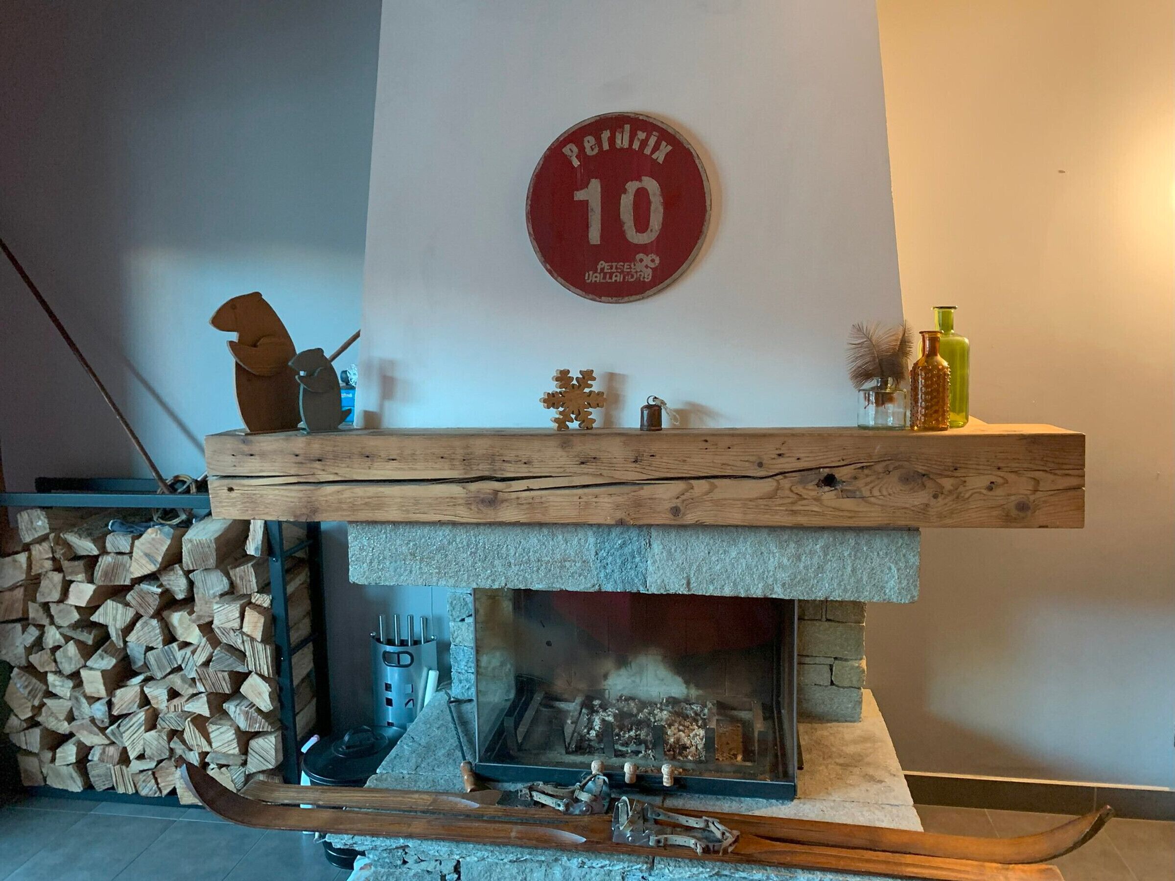 A fireplace with a stone surround, a wooden shelf above it, and a wall-mounted sign.