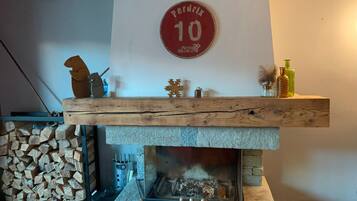 A fireplace with a stone surround, a wooden shelf above it, and a wall-mounted sign.