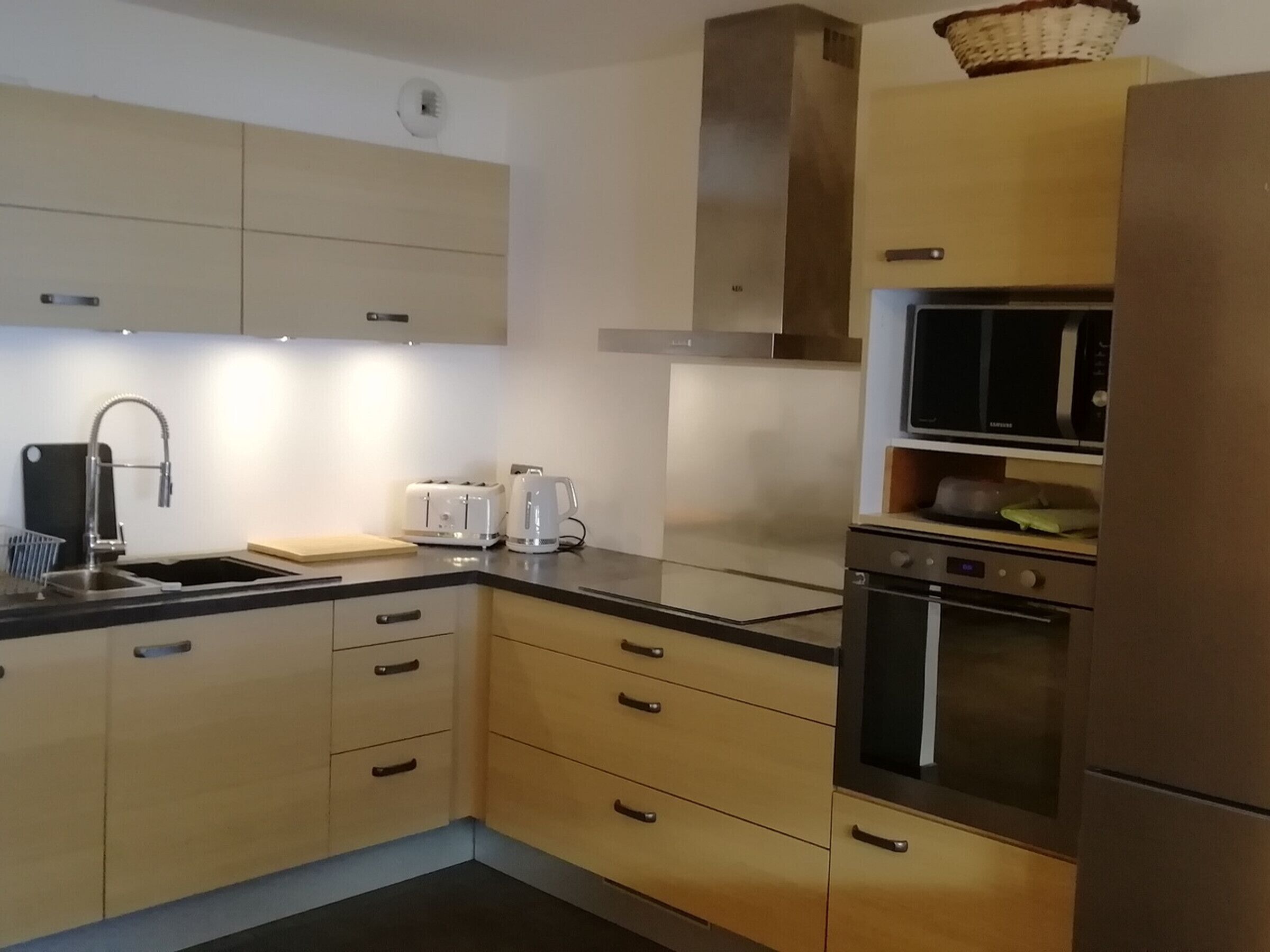 A modern kitchen with a stainless steel sink, a toaster, a kettle, and a microwave.